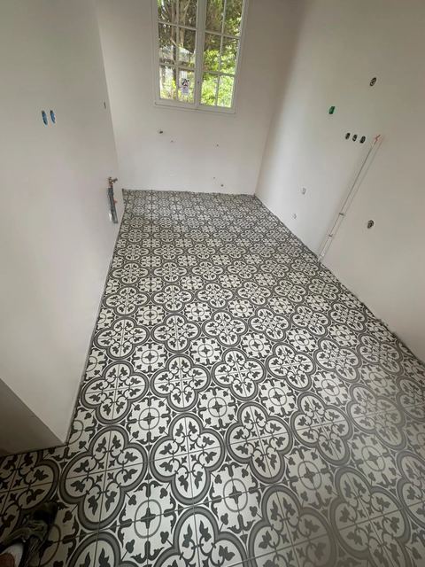 Sol en carreaux de ciment à motifs gris et blancs dans une pièce en rénovation