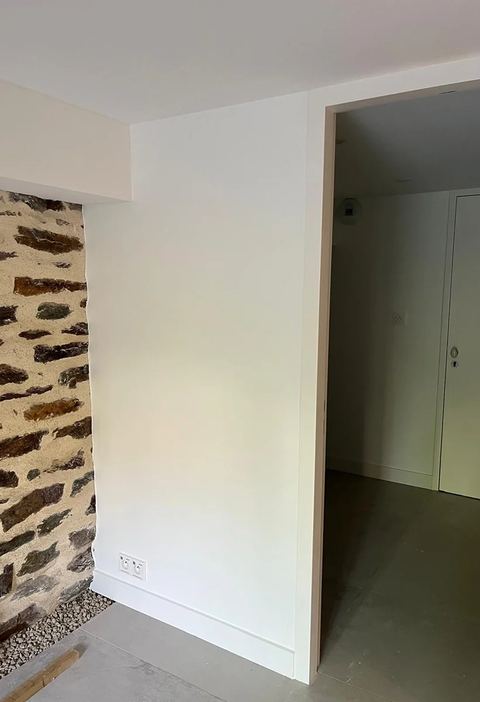 Couloir rénové, cloison en plaques à côté d'un mur en pierre apparente