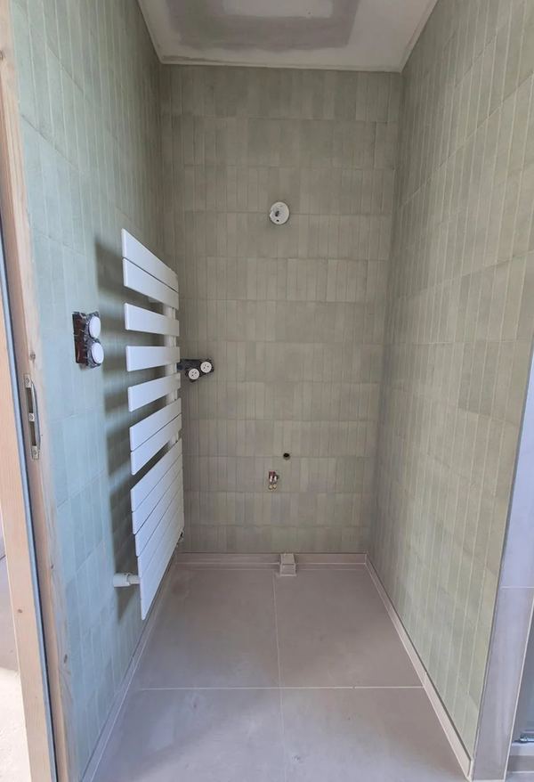 Salle d'eau carrelée en beige avec sèche-serviette