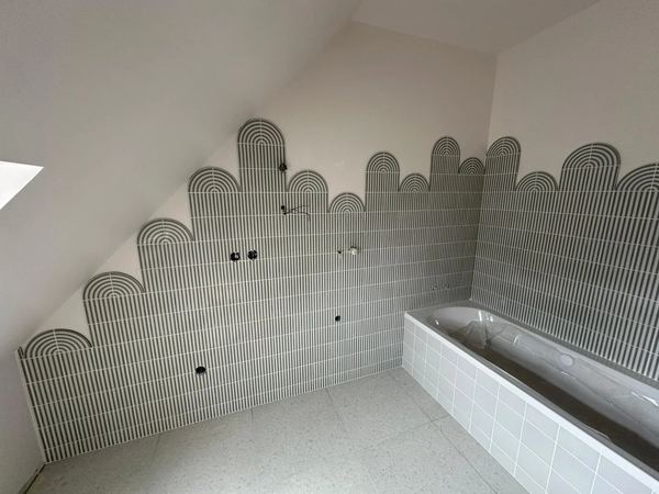 Salle de bain sous rampant, mur en mosaïque écailles au-dessus de la baignoire