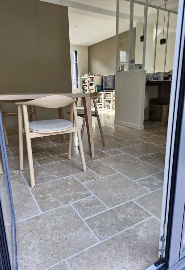 Salle à manger au sol carrelé effet pierre, verrière d'atelier