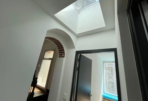Plafond en plaques de plâtre avec fenêtre de toit et arche en briques apparentes