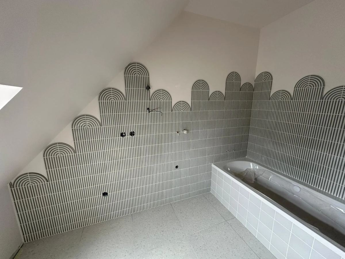 Salle de bain sous rampant, mur en mosaïque écailles au-dessus de la baignoire